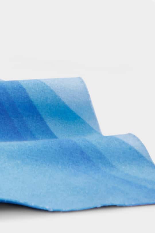 Microfiber lens cloth with different shades of blue in a wave pattern.